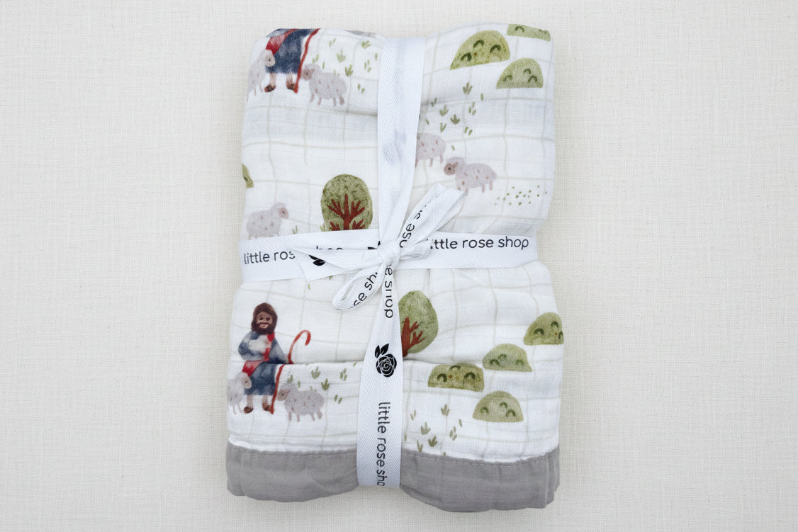 Baby blanket with sheep and shepherd pattern tied together with a white ribbon