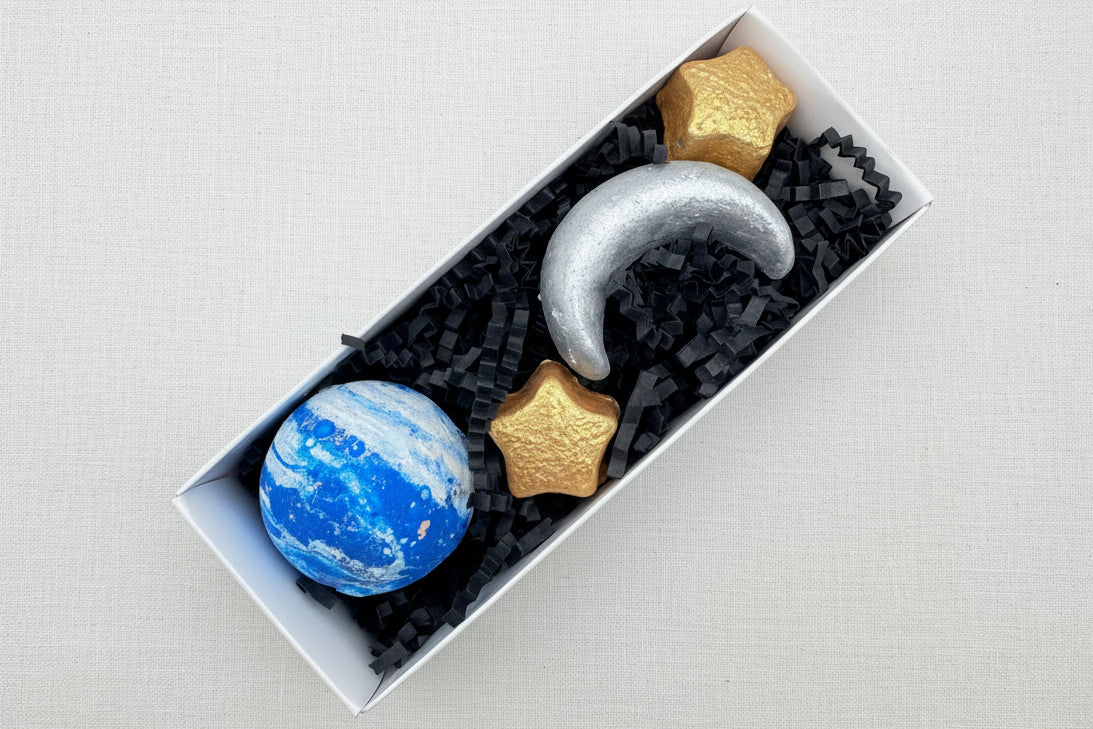 Sidewalk chalk in the shape of planets and stars in a box with black tissue paper.
