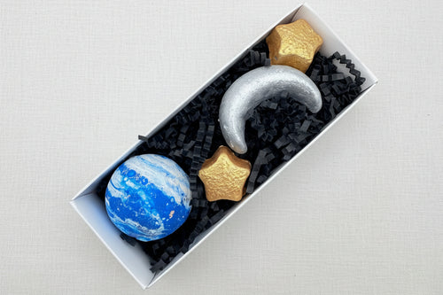 Load image 1 in gallery view. Sidewalk chalk in the shape of planets and stars in a box with black tissue paper.
