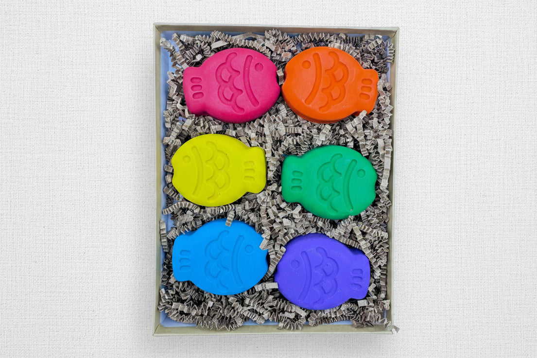 Set of six colorful fish-shaped crayons in a box 