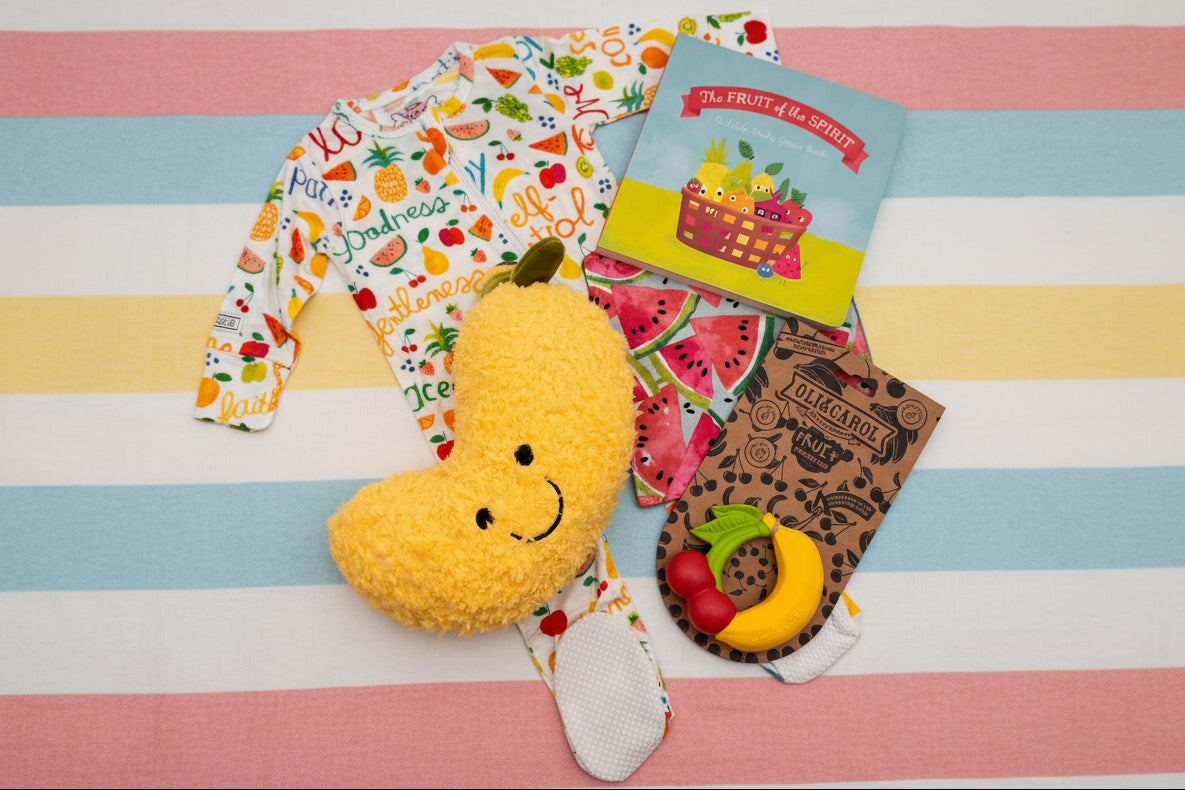 Infant items, including banana plush toy, fruit-shaped teether, and book 