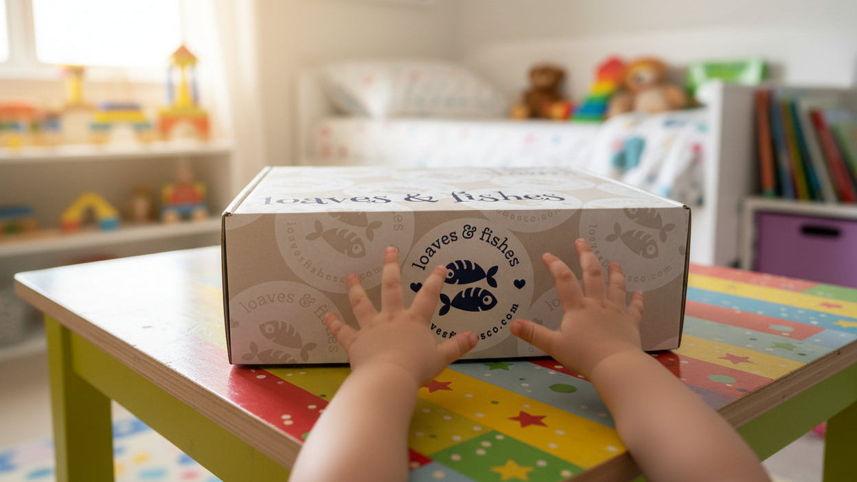 Child's hands reaching towards a box labeled 'Loaves & Fishes' on a colorful table in child's bedroom