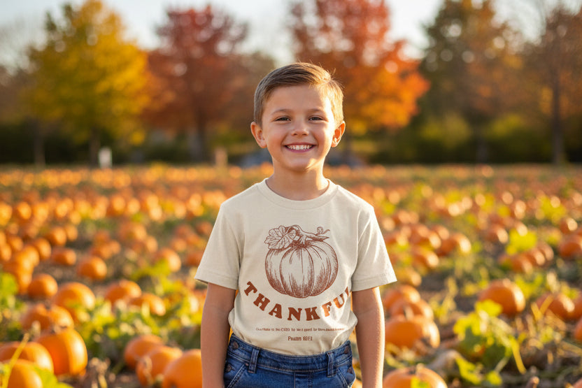 Child standing in pumpkin patch and smiling