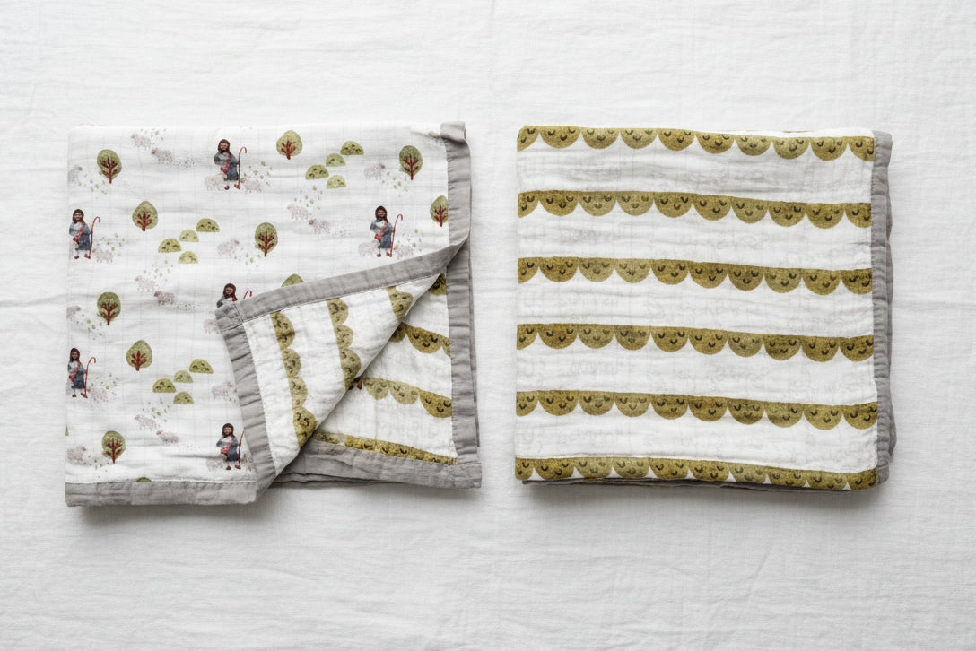 Child's blanket with illustration of a shepherd, sheep, and trees on a white background