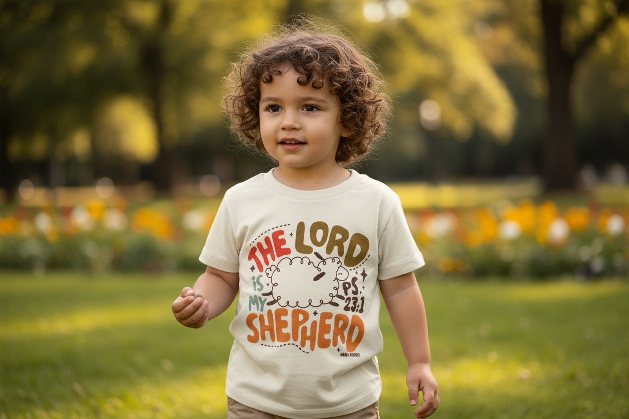 Child wearing a shirt with 'The Lord is my Shepherd' in a park setting